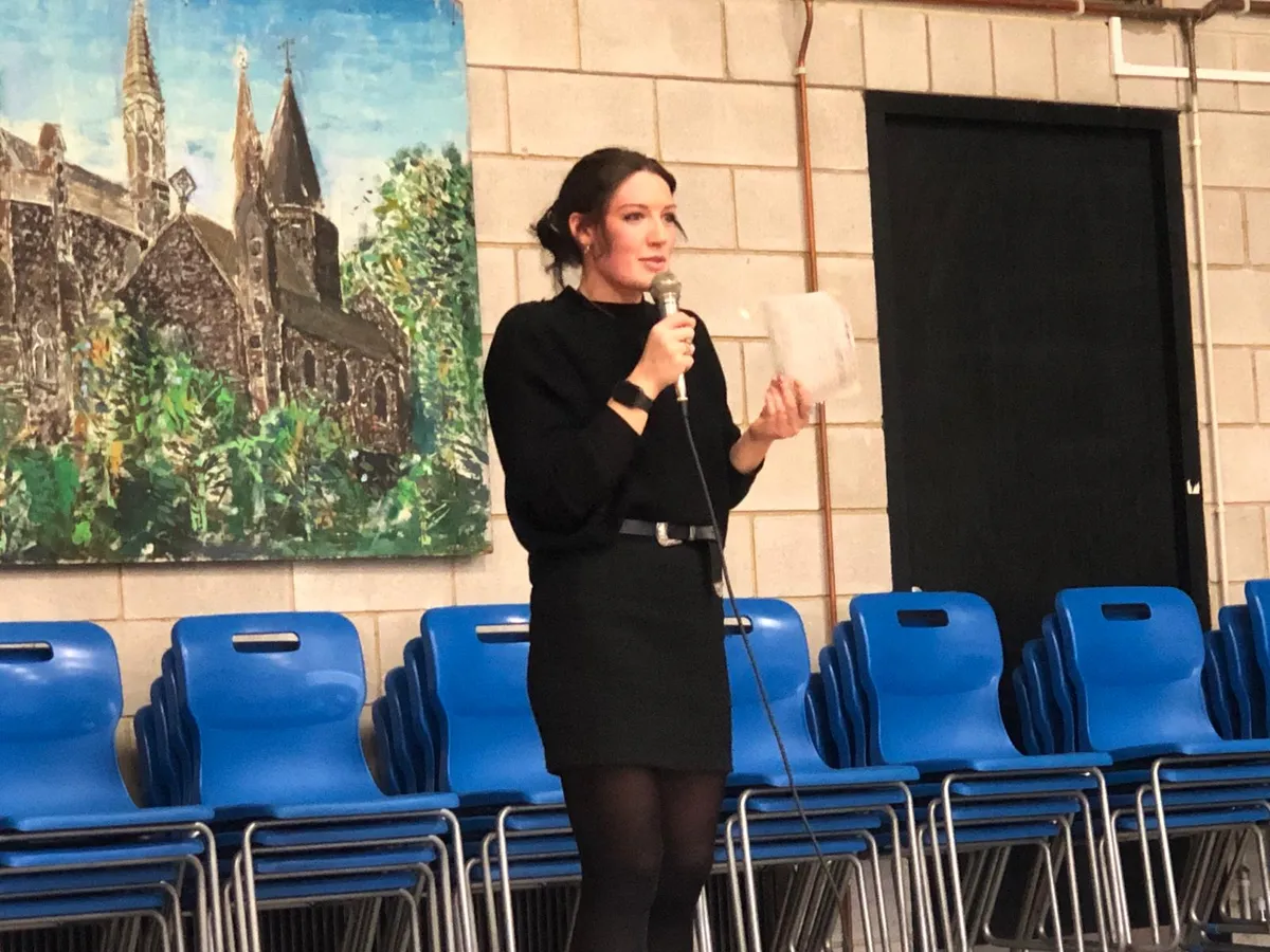 Cassandra speaking into a microphone in a school hall