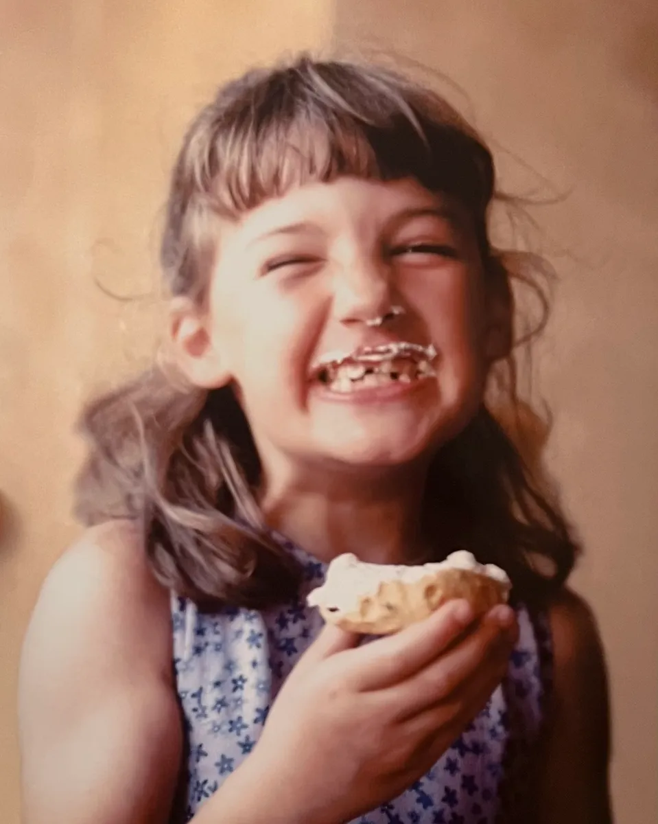 Cassandra as a child, laughing with cream on her face