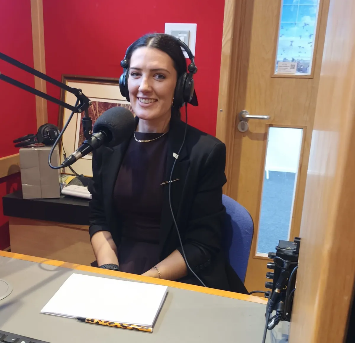 Cassandra in a radio studio, wearing headphones at the microphone